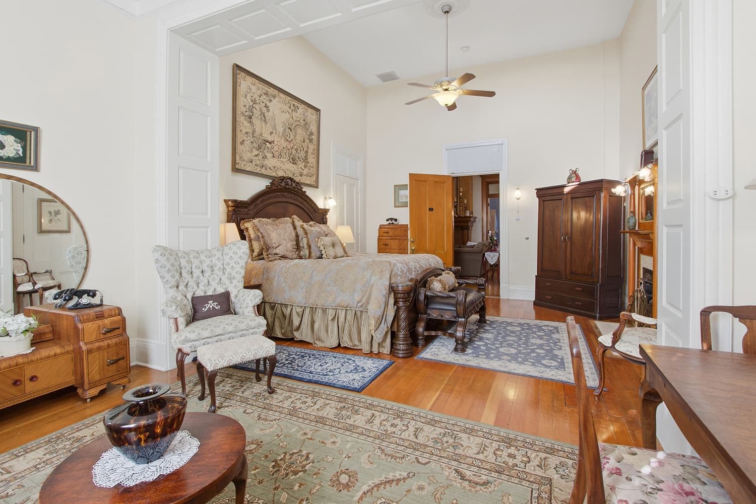 A cozy bedroom featuring a large bed, vintage furniture, and warm decor.