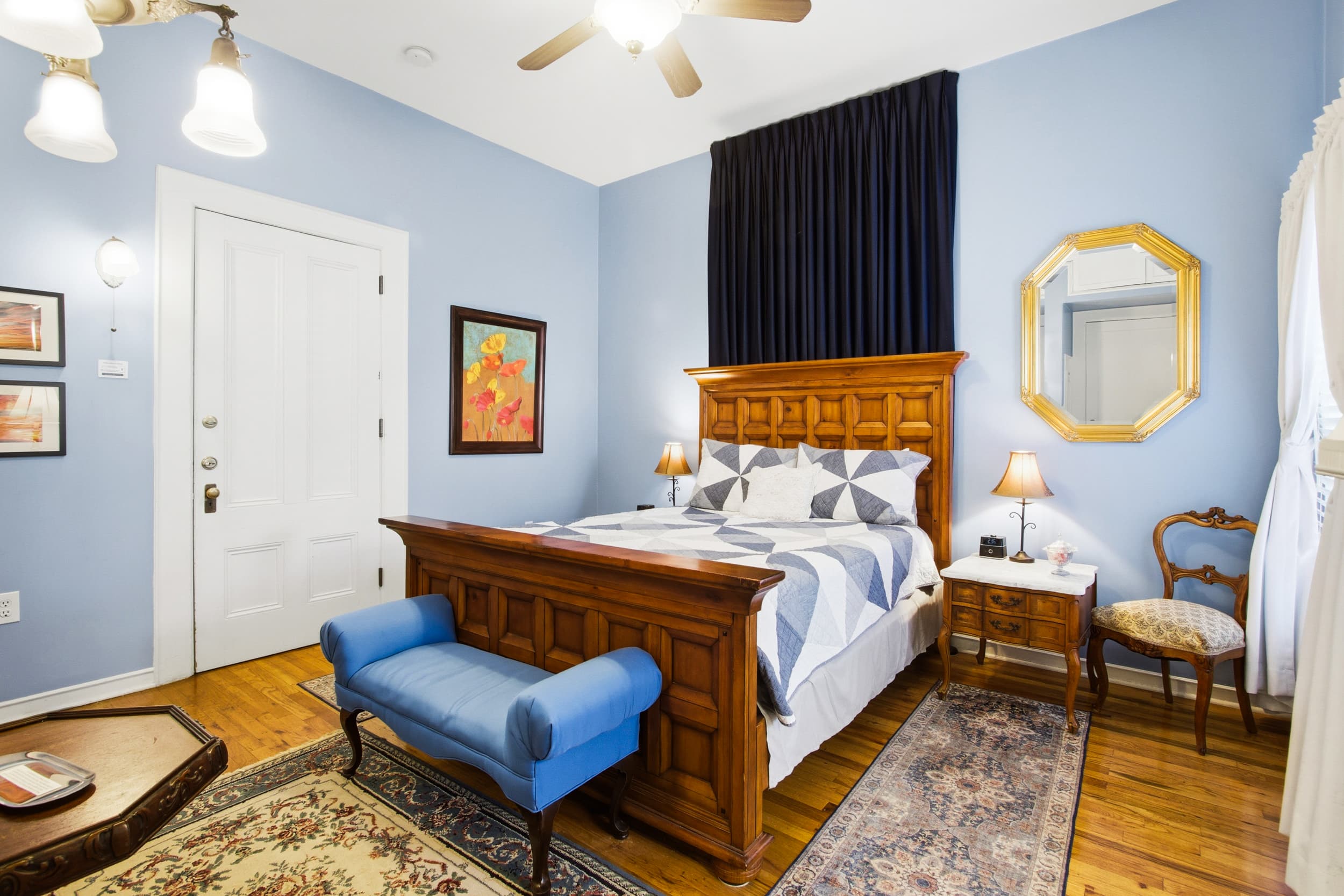 A cozy bedroom featuring a wooden bed, blue accents, and soft lighting.