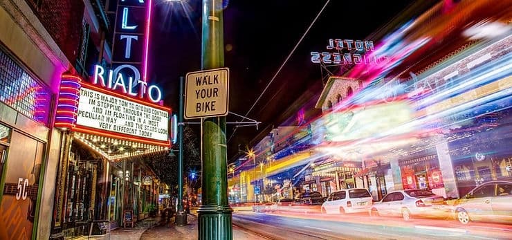 A vibrant nighttime street scene featuring the illuminated Rialto Theater marquee and light trails from passing cars. A vibrant nighttime street scene featuring the illuminated Rialto Theater marquee and light trails from passing cars.