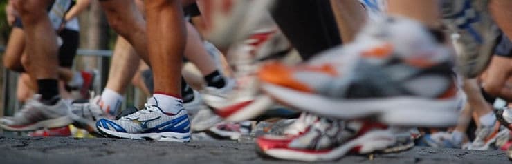 A close-up of running shoes as participants race along a track. A close-up of running shoes as participants race along a track.