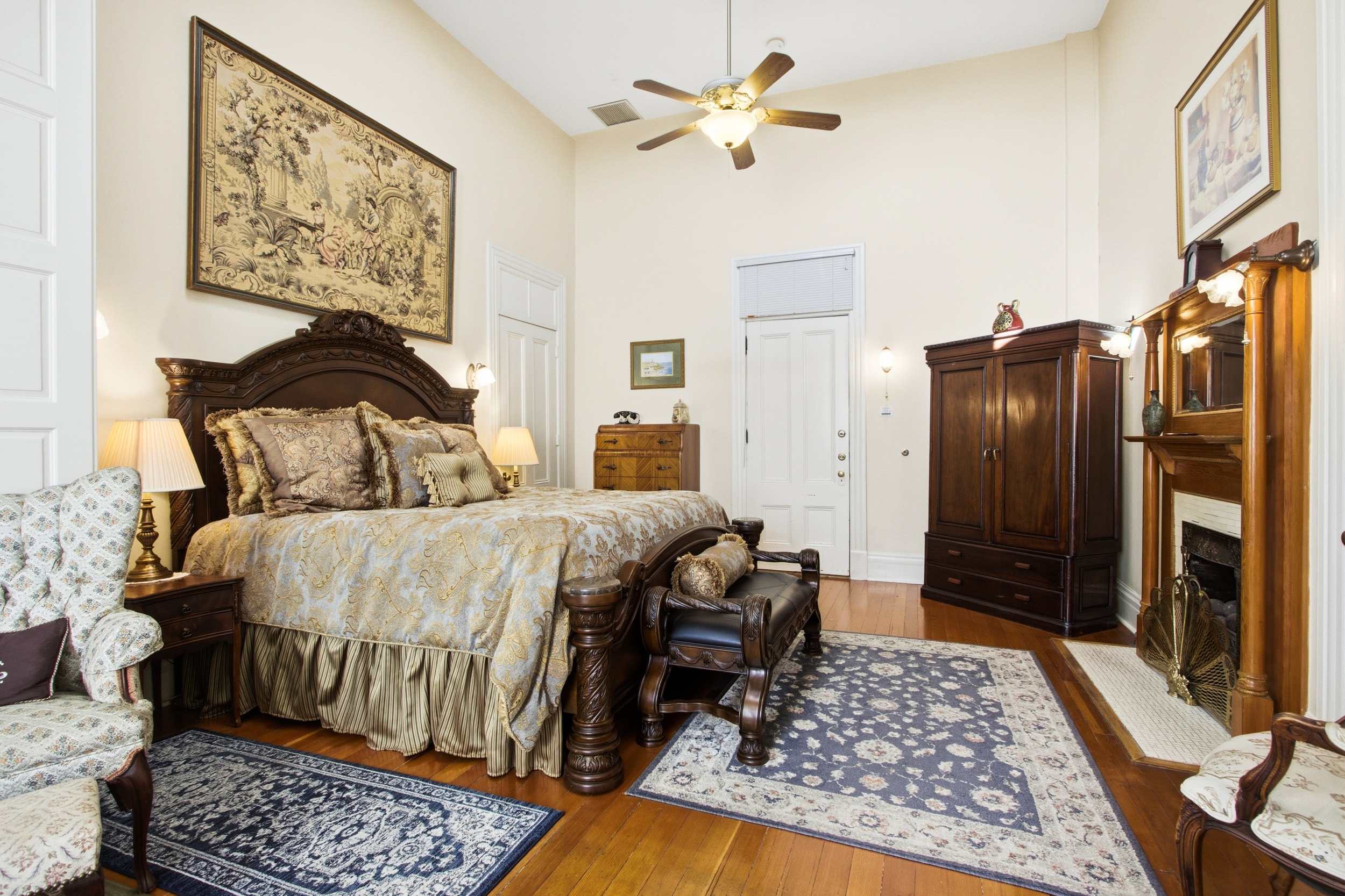 A beautifully decorated bedroom featuring a large bed, elegant furniture, and warm wooden accents.