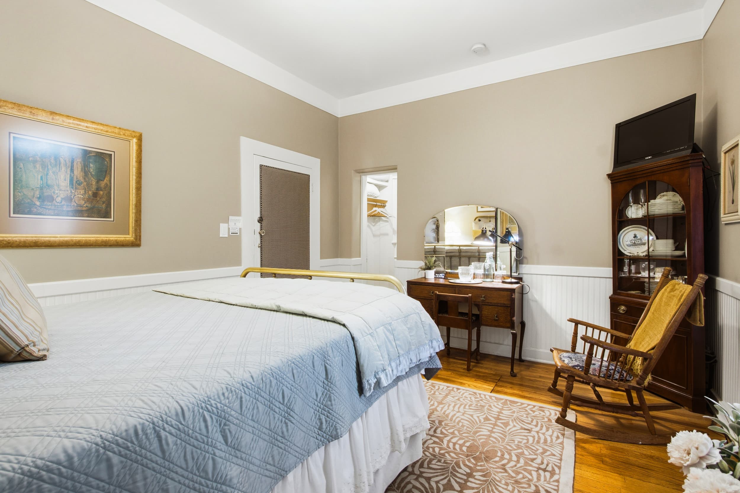 A cozy bedroom featuring a bed, vintage furnishings, and a small vanity.